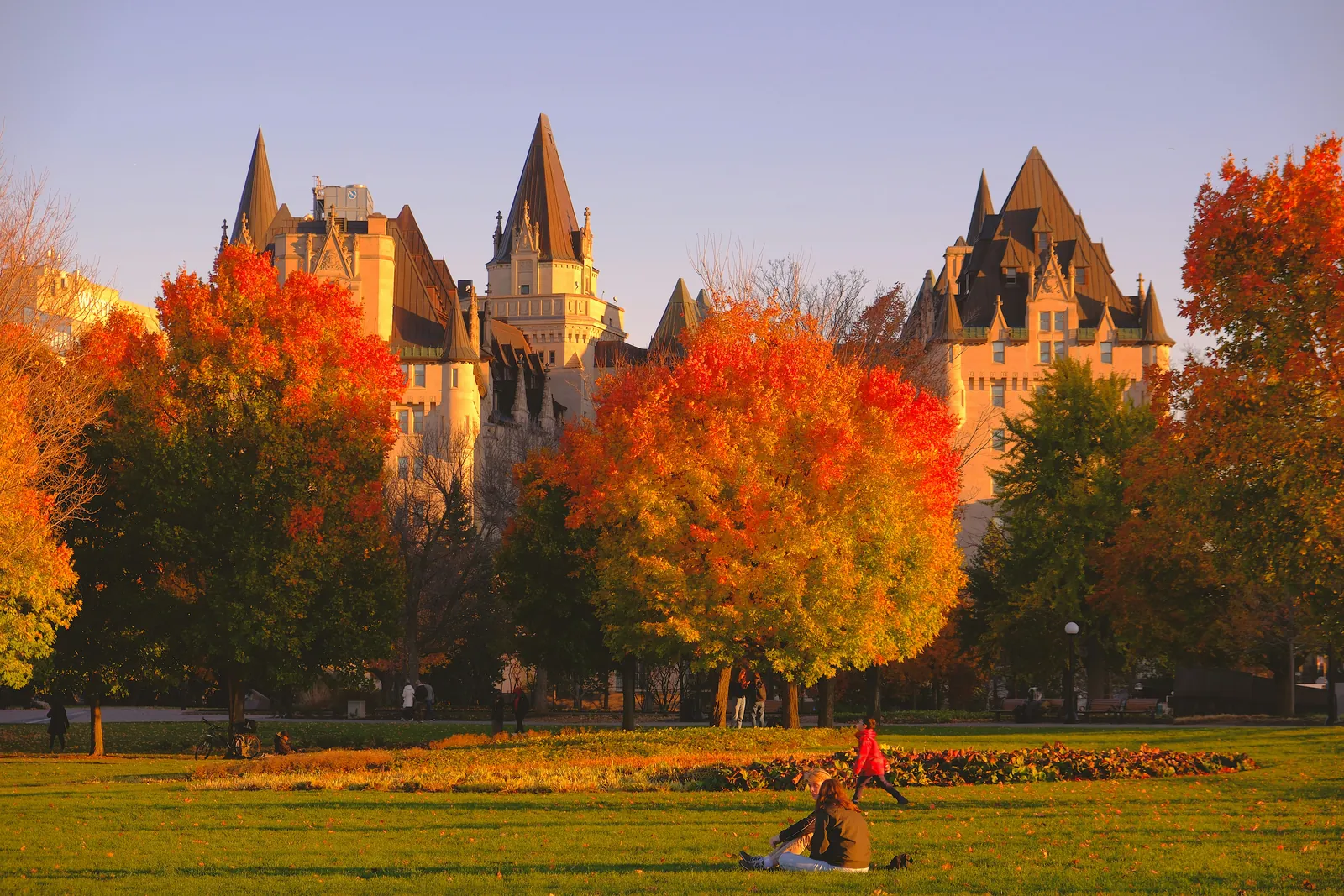 Des arbres d'automne orange et rouges devant le Château Laurier, à Ottawa, dans la lumière du soir.